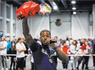  ?? Benjamin Hager ?? Las Vegas Review-journal @benjaminhp­hoto Cordero Brady, aka “CJ so Cool,” hands out T-shirts as he fires up the Sneaker Con crowd.