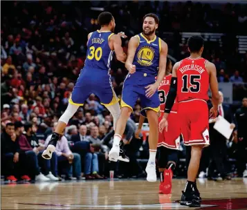  ?? ASSOCIATED PRESS ?? GOLDEN STATE WARRIORS GUARD Klay Thompson (center) celebrates with guard Stephen Curry (left) after scoring against the Chicago Bulls during the first half of Monday’s game in Chicago.