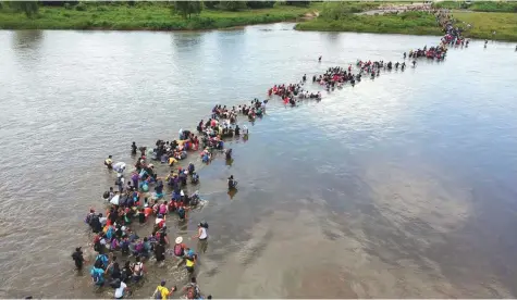  ?? AFP ?? Top and below left: Salvadorea­n migrants heading in a caravan to the United States, cross the Suchiate River to Mexico, from Ciudad Tecun Uman, Guatemala, on Friday. Below right: Migrants, part of a caravan travelling from Central America en route to the US, walk by the road that links Ciudad Hidalgo with Tapachula.