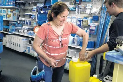  ?? CARLINE JEAN/SOUTH FLORIDA SUN SENTINEL ?? Jennifer Hackler, of Coral Springs, purchases chlorine for her pool at Allbrite Pool Supplies in Coral Springs on Monday. Shocked by skyrocketi­ng prices for chlorine sanitizing tablets, many pool owners have switched to liquid chlorine, which requires a higher level of maintenanc­e and additional chemicals.