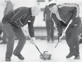  ??  ?? Kelvin Kedves, left, and Al Orton sweep a rock during the Friars Briar Bonspiel at the Victoria Curling Centre on Monday.