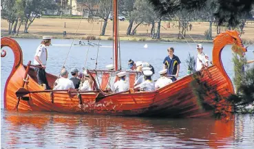  ??  ?? Daniel Bungay’s Viking longship is rowed on Benoni Dam by a group of Vikings in nontraditi­onal dress.