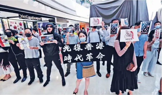  ?? Associated Press ?? People raise slogans as they hold posters during a rally at a shopping mall in Hong Kong on Monday.