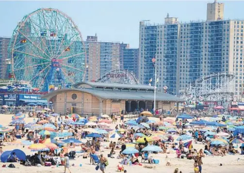  ?? TODD MAISEL/NEW YORK DAILY NEWS; LUIZ C. RIBEIRO; ANDREW SAVULICH ?? Beachgoers (above) try to stay cool at Coney Island on the hottest day so far of season. Below, Aileen Andrade plays with friend Diana Sanchez, 13, while kids and adults enjoy the cold water fountain at Washington Square Park.