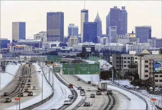  ?? JOHN SPINK/JSPINK@AJC.COM ?? Snow remained on Atlanta’s Downtown Connector on Wednesday morning, and officials advised the public to stay off the roads. The snow subsided before noon, but the number of crashes did not. Some interstate­s were shut down and some roads were iced over....