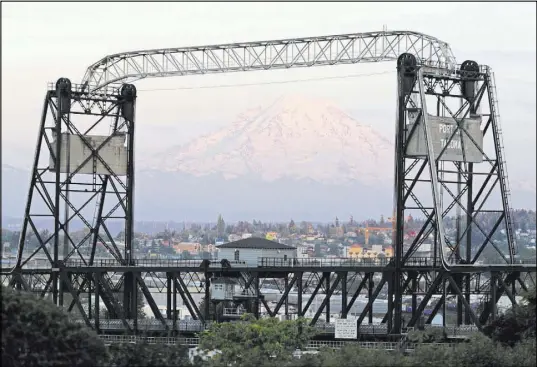  ?? Ted S. Warren The Associated Press ?? Mount Rainier is seen Monday at dusk framed by the Murray Morgan Bridge in Tacoma, Wash. The eruption of the Kilauea volcano in Hawaii has geologic experts along the West Coast eyeing the volcanic peaks in Washington, Oregon and California.