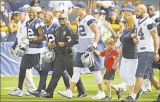  ??  ?? Dallas Police Chief David Brown, center, walks with Magnus Ahrens, 8, son of slain Dallas officer Lorne Ahrens), his aunt Erika Swyryn and members of Cowboys including owner Jerry Jones (l.) in ceremony prior to team’s first practice.