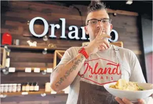  ?? RICARDO RAMIREZ BUXEDA/ORLANDO SENTINEL ?? Eliot Hillis, chef/owner of Orlando Meats, holds the Marty Feldman, a secret menu item made of corned beef, Thai chili fancy sauce, scallion, fried egg, zaftig noodle.