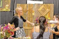  ?? Appeal-Democrat file photo ?? Kim Pedley, co-owner of Township Valley Farm, shares a laugh over scoops of pesto at last year’s Taste of Yuba-Sutter.