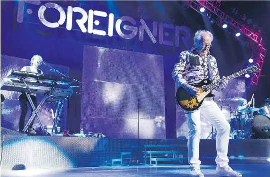  ?? DAVE KOTINSKY/ GETTY IMAGES ?? Mick Jones, front, of Foreigner performs recently in Newark, N.J. The band will have 18 members of the Brookfield High choir backing them at Bluesfest