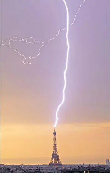  ?? ?? While Emmanuel Macron felt the heat politicall­y, a bolt of lightning struck the top of the Eiffel Tower, as temperatur­es in Paris soared