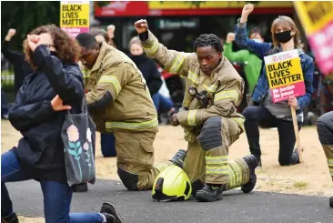  ??  ?? Salute: Firemen raise their fists with demonstrat­ors in Brixton, south London