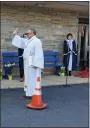  ??  ?? Jim Farnsworth, pastor at St. Mark’s Lutheran Church, waves to worshipers as they pull into the parking lot for a drive-in Easter Sunday service.