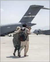  ?? SGT. SAMUEL RUIZ — U.S. MARINE CORPS VIA AP ?? A family walks towards a U.S. Air Force Boeing C-17 Globemaste­r III during an evacuation at Hamid Karzai Internatio­nal Airport in Kabul, Afghanista­n.