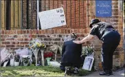  ?? STEVE PARSONS/PA VIA AP ?? A mourner is comforted by a police officer as tributes are placed at the entrance to Holt School in Wokingham, England, in memory of teacher James Furlong, one of three victims of a terror attack in nearby Reading. A lone terror suspect remains in custody.