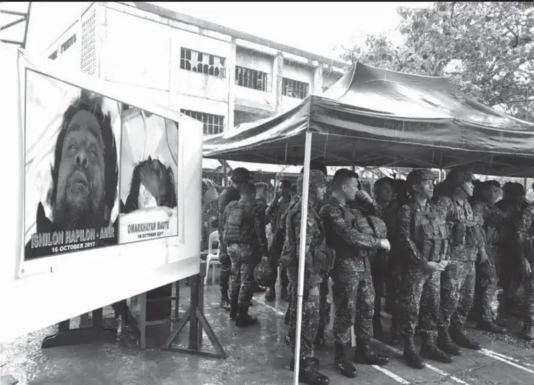  ?? (AP) ?? Philippine troops stand beside photos of dead militant leaders Isnilon Hapilon and Omarkhayam Maute in Marawi, southern Philippine­s on Tuesday Oct. 17, 2017.