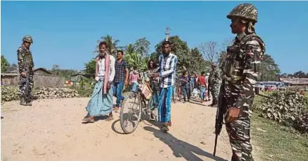  ??  ?? Villagers walking past Central Reserve Police Force personnel patrolling a road ahead of the publicatio­n of the first draft of the National Register of Citizens in the Juria village of Nagaon district in Assam on Thursday.