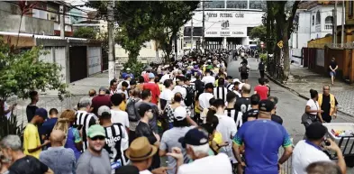  ?? ?? Pitch perfect: Mourners in yellow, and black and white shirts at Urbano Caldeira stadium