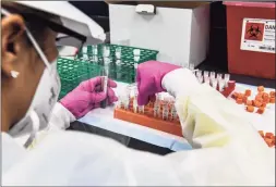  ?? Chandan Khanna / Getty Images ?? In this file photo taken on Aug. 13, a lab technician sorts blood samples for a COVID-19 vaccinatio­n study at the Research Centers of America in Hollywood, Fla.