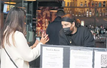  ?? KELSEY WILSON TORONTO STAR ?? A patron shows proof of vaccinatio­n to Mackenzie Irons at the Corner Place near Front and Jarvis streets on Wednesday.