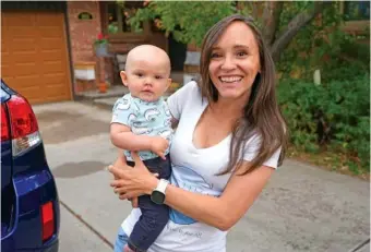  ?? AP PHOTO/DAVID ZALUBOWSKI ?? Carrie Martin-Haley holds her son outside their home Friday in Greenwood Village, Colo.