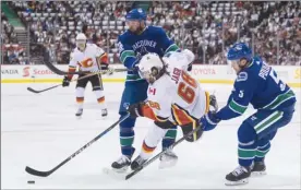  ?? The Canadian Press ?? Calgary Flames forward Jaromir Jagr is checked to the ice by Thomas Vanek of the Vancouver Canucks in front of Derrick Pouliot during first-period NHL action in Vancouver on Saturday.