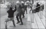  ?? AP/THANASSIS STAVRAKIS ?? A protester attacks a police officer with a hammer Wednesday in Athens as an anti-austerity demonstrat­ion in the Greek capital turned violent.