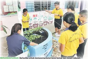  ??  ?? BERSIHKAN SUNGAI: Berlumba untuk memancing botol-botol keluar dari kolam sekolah.