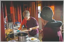  ??  ?? Mary Ann Unson serves food to her mother Lou Ann Trahan, who lives with her and suffers from dementia, on Christmas Eve inside their gutted home. They are living in a camper on their property, while other relatives are living in tents and campers there as well, all of whom lost their home to the storms.