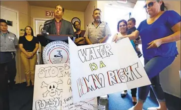  ?? Mel Melcon Los Angeles Times ?? INTERIM General Manager Thomas Martin, left, addresses reporters Sept. 10 at the Sativa Los Angeles County Water District’s headquarte­rs as activist Maria Estrada of Lakewood sets down a protest sign.