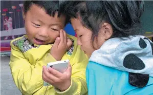  ?? XINHUA ?? Two kids in Yangshang county, Anhui province, play games on a mobile phone.