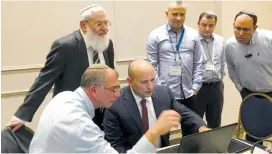  ?? (Bayit Yehudi) ?? BAYIT YEHUDI leader Naftali Bennett (seated, center) oversees results of the vote in the party election committee’s situation room in Jerusalem on Monday.