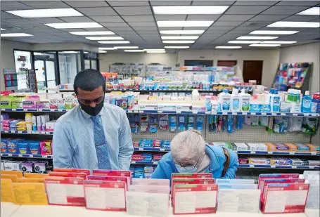  ?? SARAH GORDON/THE DAY ?? Pharmacy Manager Jason Navallil, left, helps customer Carol Golart, of Waterford, at the new Nutmeg Pharmacy location in New London on Monday. “I’ve been waiting for this place to open, to have a local pharmacy,” said Golart.