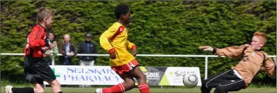  ??  ?? Festy Ebosele skips between Jason Bolger and netminder Alan Hayes to score one of his three goals for Moyne Rangers.