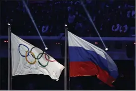  ?? ASSOCIATED PRESS FILE PHOTO ?? The Russian national flag, right, flies after it is hoisted next to the Olympic flag during the closing ceremony of the 2014 Winter Olympics in Sochi, Russia.