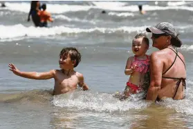  ??  ?? Jaden Green, 4, plays in the water with Teri Young and Young’s 18-moth-old daughter, Emmi, on Stewart Beach on Friday.