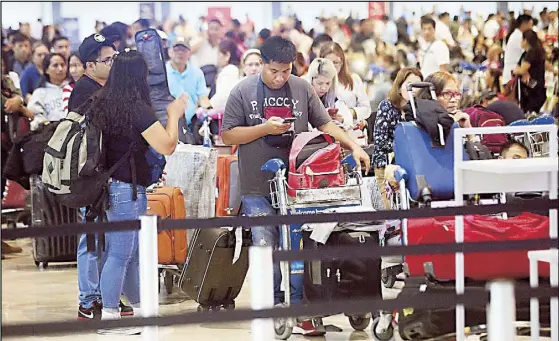  ?? RUDY SANTOS ?? Passengers line up at the Kuwait Airlines check-in counter at the NAIA the other night. Some of the passengers were overseas Filipino workers returning to Kuwait while others were bound for Italy via the Gulf state.