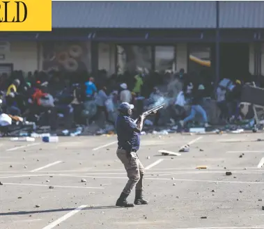  ?? GUILLEM SARTORIO / AFP VIA GETTY IMAGES ?? A member of the South African Police Service fires rubber bullets at rioters looting the Jabulani Mall in Soweto,
southwest of Johannesbu­rg, on Monday, amid unrest sparked by the jailing of ex-president Jacob Zuma.