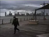  ?? MARK LENNIHAN — ASSOCIATED PRESS ?? A woman wears a face mask as she walks on Pier 45 in Hudson River Park on Thursday evening in New York.