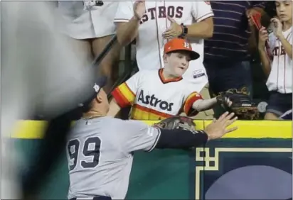  ?? THE ASSOCIATED PRESS ?? A young fan catches a home run hit by Houston Astros’ Carlos Correa in front of Yankees’ Aaron Judge (99) during the fourth inning of Game 2.