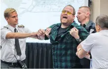  ?? PAUL CHIASSON/THE CANADIAN PRESS ?? Security guards try to restrain a demonstrat­or from interrupti­ng the National Energy Board public hearing into TransCanad­a’s proposed $15.7-billion Energy East pipeline project last August in Montreal.