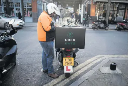  ?? Photos: Simon Dawson/Bloomberg via Getty Images ?? A food courier prepares to deliver an Uber Eats order in London. The food delivery business model has proven attractive to venture capitalist­s, who last year poured $5.5-billion into food-delivery companies globally, according to research firm CB Insights.