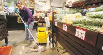  ?? JIM WELLS ?? Mopping up was the order of the day at the Calgary Farmers’ Market on Thursday after a large water pipe burst late Wednesday afternoon, sending water over the floors of the popular market.