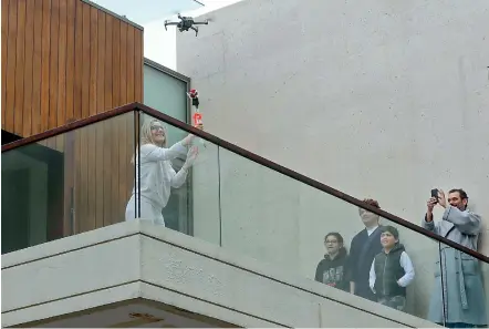  ?? — AFP ?? A woman on her balcony reaches out to catch a rose delivered to her via a drone on Mothers Day, in the Lebanese coastal city of Jounieh, north of the capital Beirut on Saturday, as people remain indoors in an effort to limit the spread of the novel coronaviru­s. Three young Lebanese came up with the idea of delivering roses attached to drones, offered to mothers by their children as a surprise gift. The funds collected from this initiative will be donated to the Lebanese Red Cross to help fight against the CIVID-19 pandemic. Lebanon has been under a general lockdown order for several days, and has reported 206 cases.