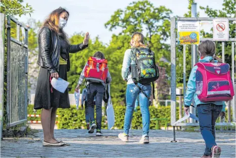  ?? FOTO: ROBERT MICHAEL / DPA ?? Lehrerin mit Mundschutz begrüßt in Dresden ihre Schüler: In Sachsen sind die Schulen seit 18. Mai wieder geöffnet. Am Montag öffnen nach monatelang­er Zwangspaus­e auch die Ellwanger Grundschul­en wieder ihre Tore.