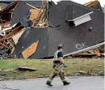  ?? AP ?? A firefighte­r surveys damage to a house after a tornado touched down south of Birmingham, Alabama.