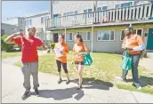  ??  ?? Thomas Wiggins, left, reads a flier he received from volunteers Mai Kader, Katie Alderman and Justin Farmer as they canvass the Goffe Street area.