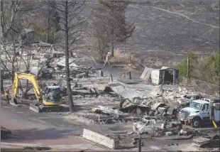  ?? The Canadian Press ?? Workers repairing power lines walk among the remains of mobile homes destroyed by wildfire in Boston Flats near Ashcroft on Sunday.