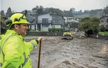  ?? ?? Resident Chris Scott contemplat­es what to do as the rain continues to fall, and more mud and water slip down Coster St.