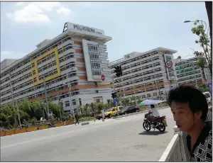  ?? (AP) ?? People walk past buildings of a Pegatron factory in Shanghai in this file photo.